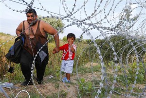 Põgenik koos lapsega Serbia ja Ungari vahelise okastraataia ääres. 